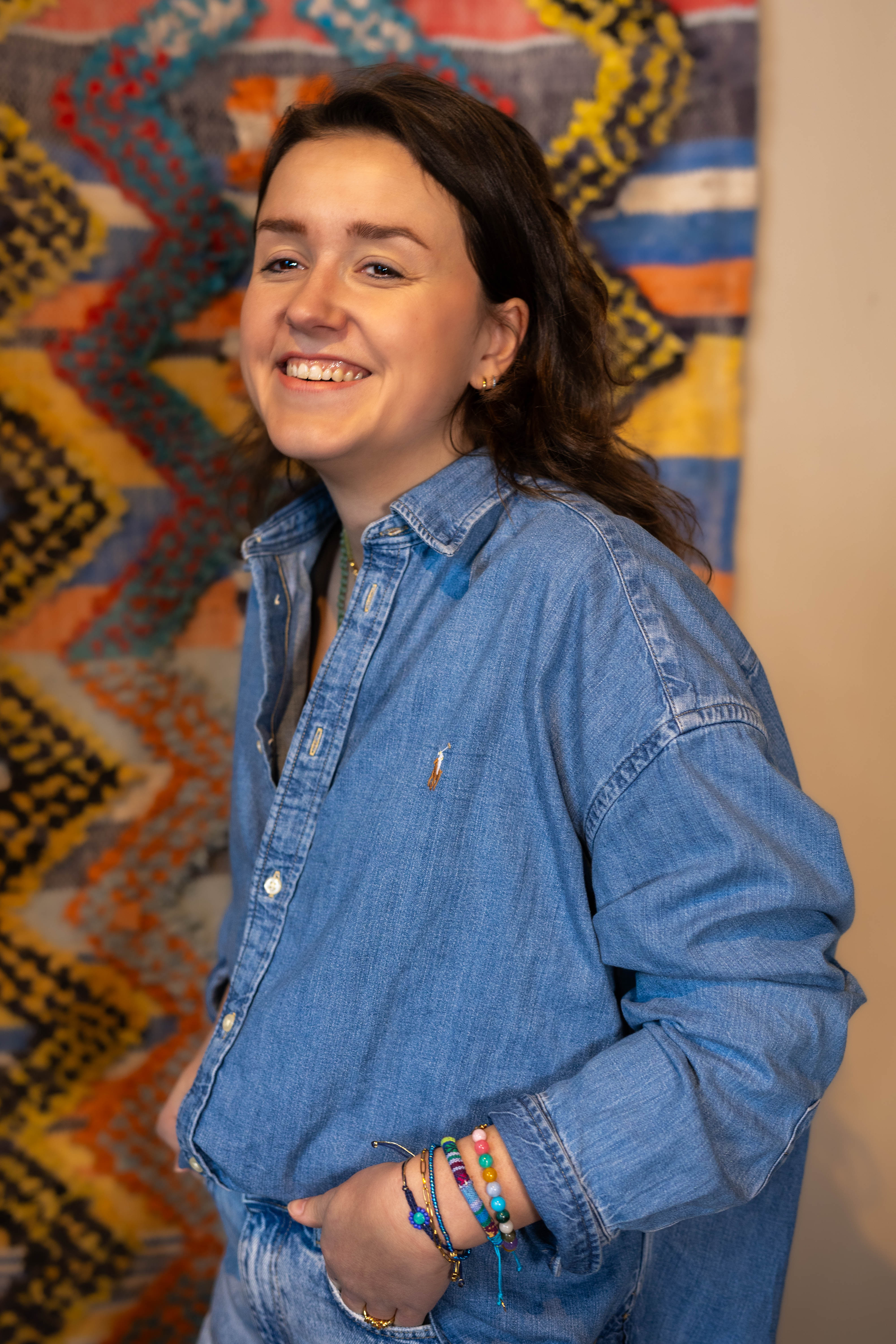 Model voor wandkleed met blauwe spijkerblouse en armbandenset van bert sieraden.