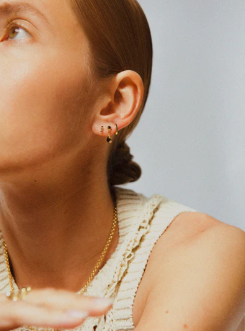 Je ziet oorbellen van Bobby Rose Jewelry in een oor. Het zijn meerdere oorbellen van swarovski en goud.