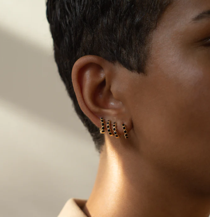 Dit is een foto van een persoon die de Bobby Rose Oorbel Black Swarovski clip oorbel in de kleur zwart en goud draagt.